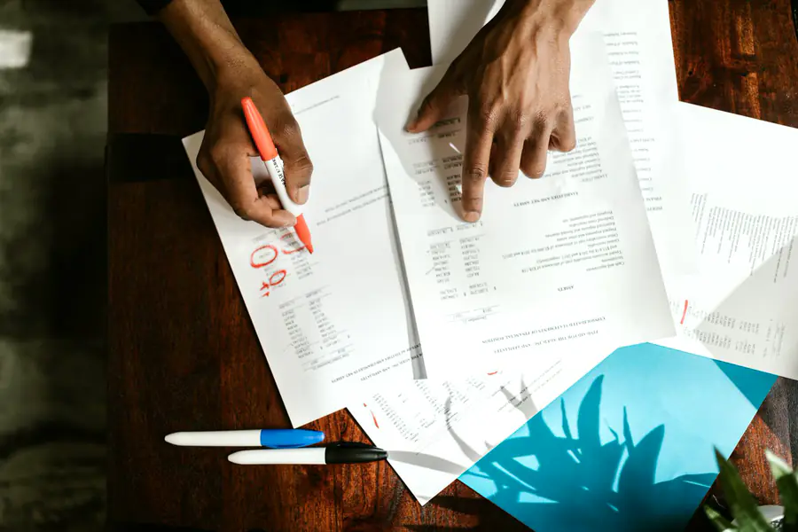Manos revisando facturas en papel con anotaciones en rojo